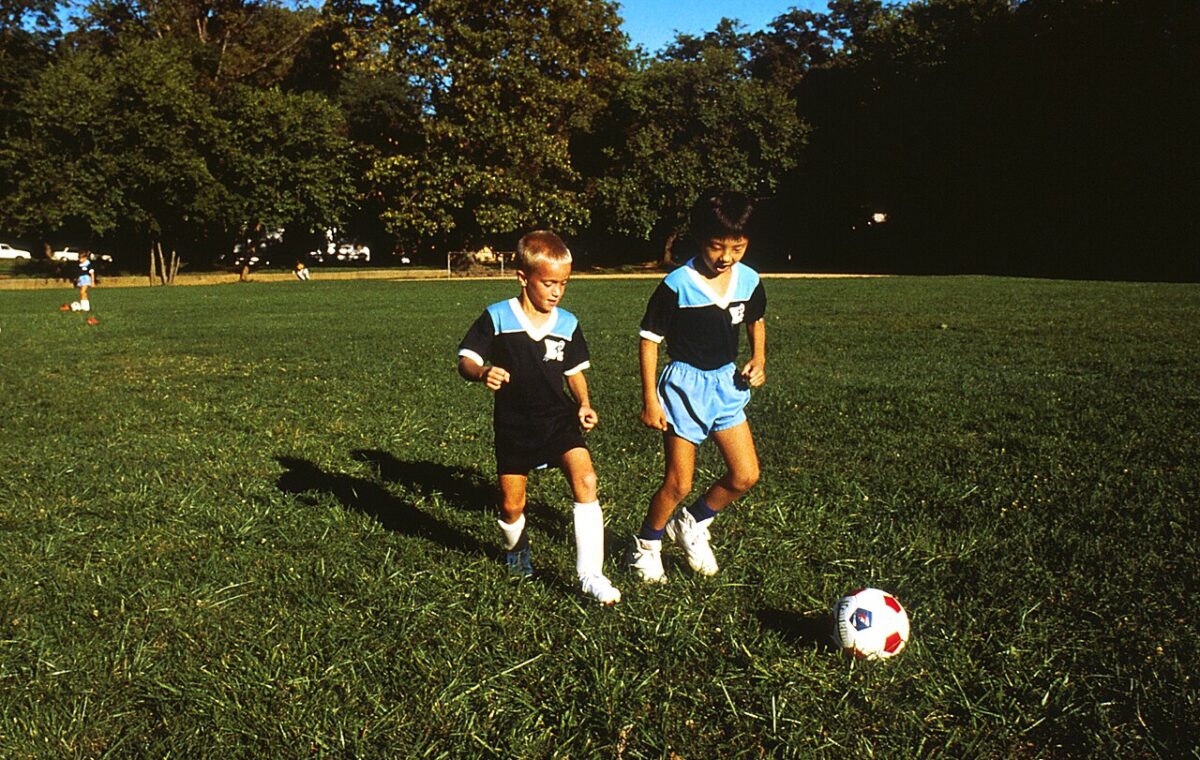Duas crianças jogando futebol em campo aberto