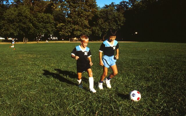 Duas crianças jogando futebol em campo aberto