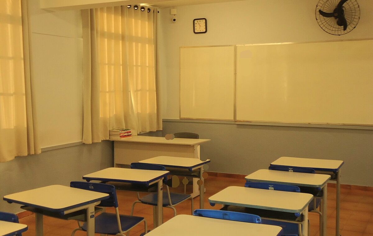 Sala de aula com carteiras e quadro, usada como imagem ilustrativa sobre educação