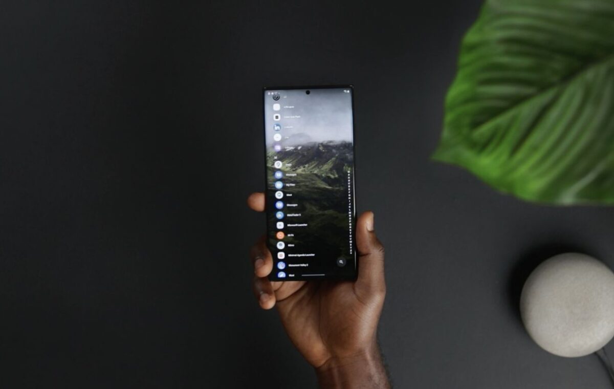 Pessoa segura smartphone com aplicativos visíveis na tela