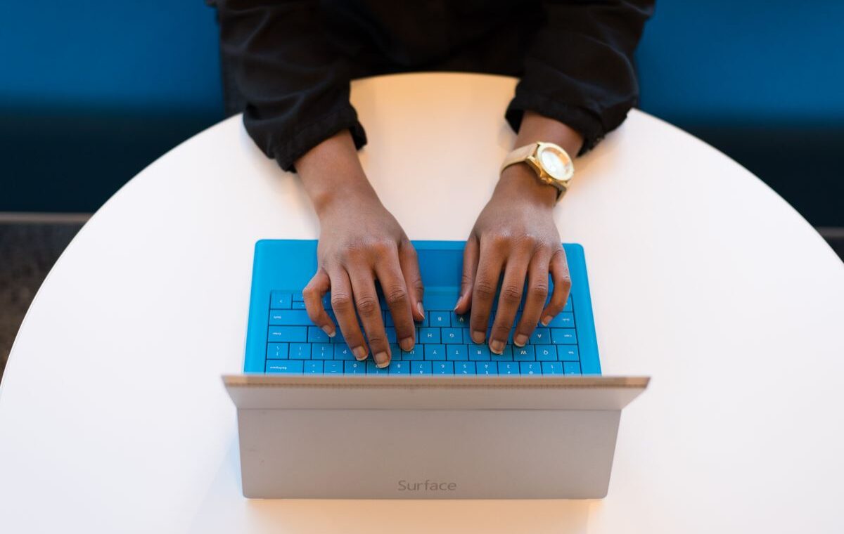 Mãos de uma pessoa digitando no teclado de um notebook