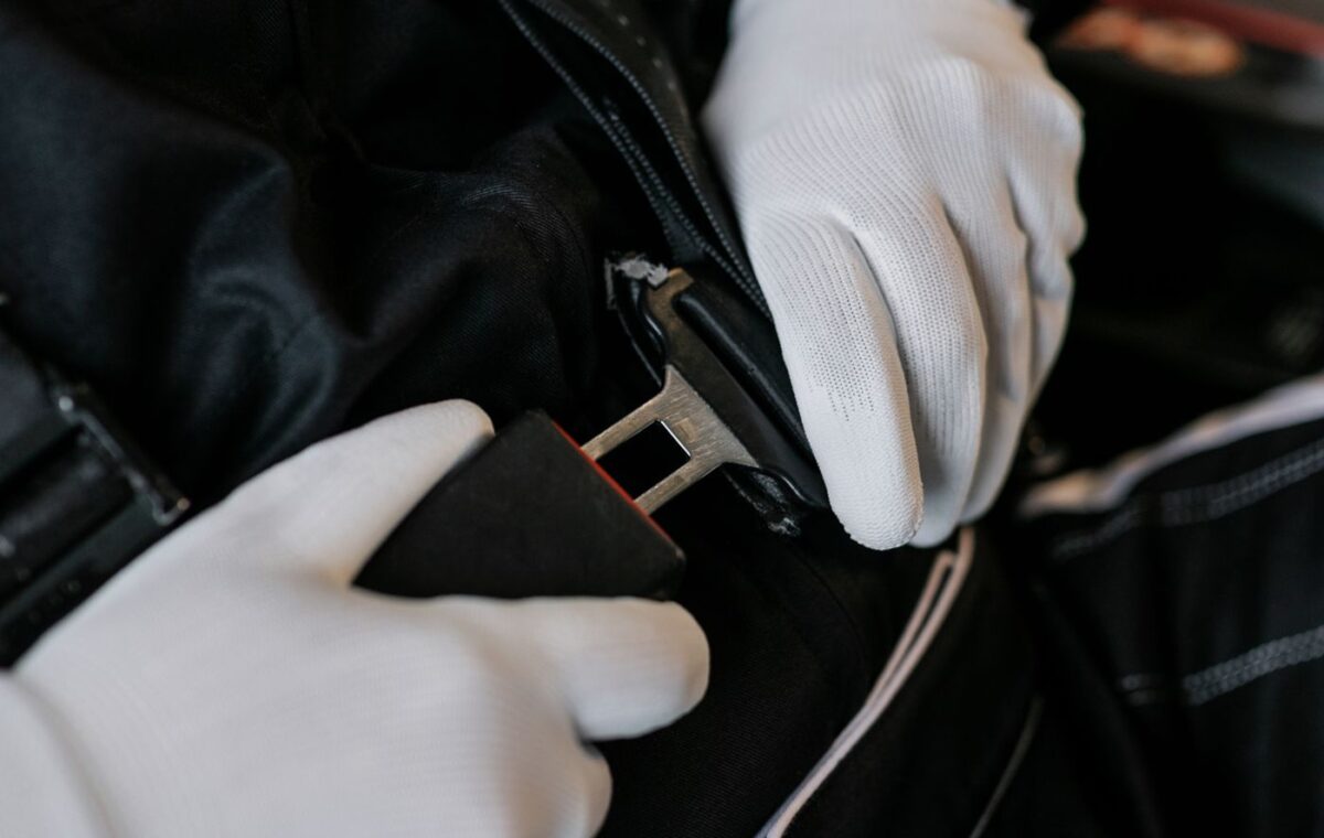 Mãos afivelando o cinto de segurança no interior de um veículo