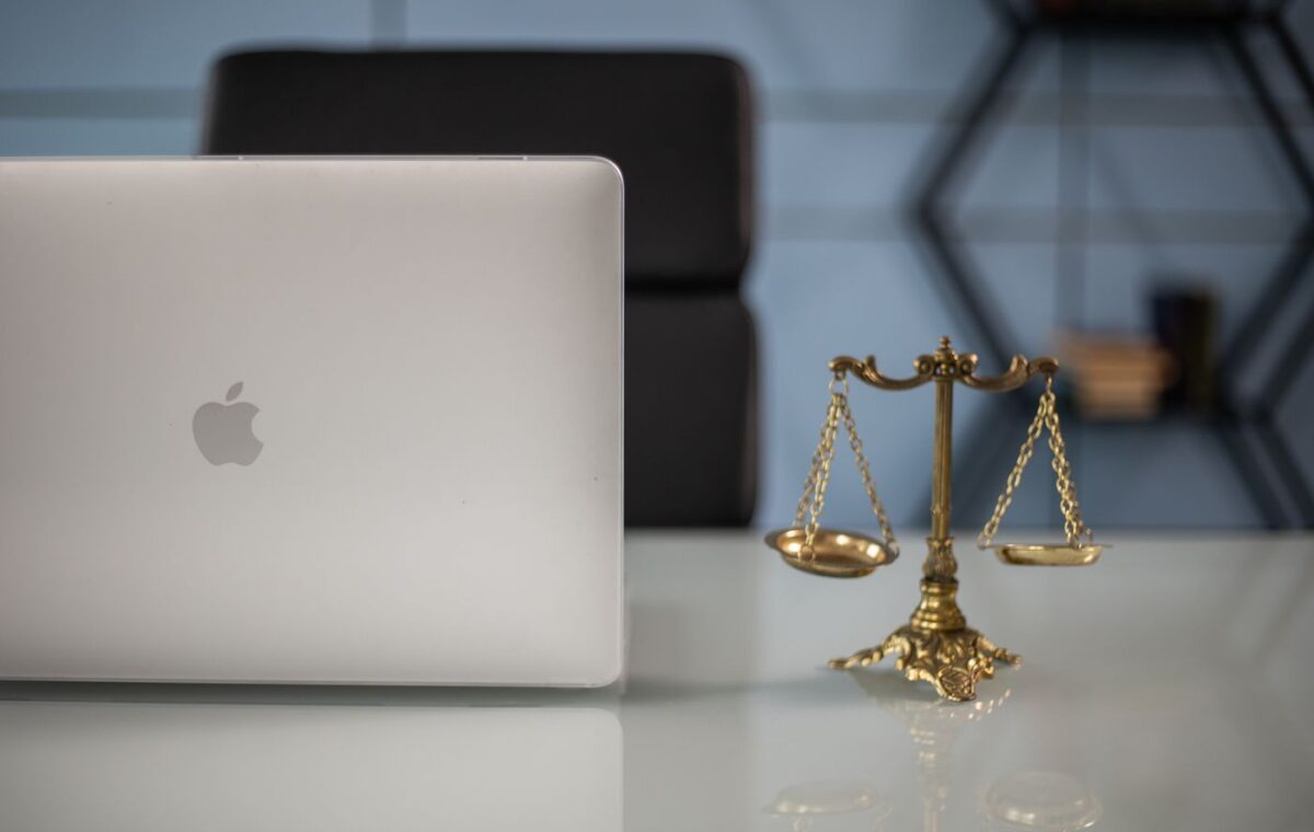 Balança da Justiça ao lado de um computador portátil sobre uma mesa