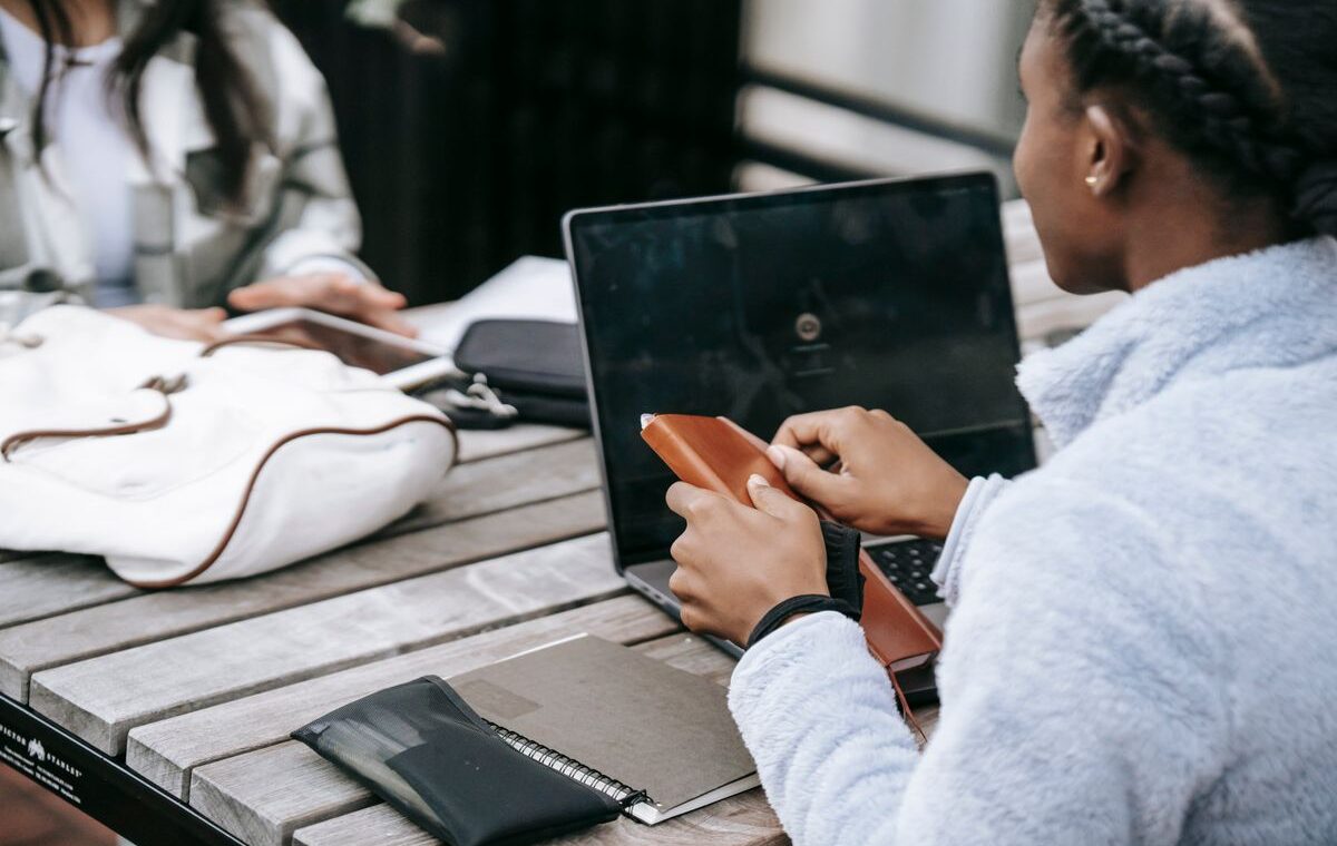 Duas estudantes trabalham em uma pesquisa com notebook e caderno