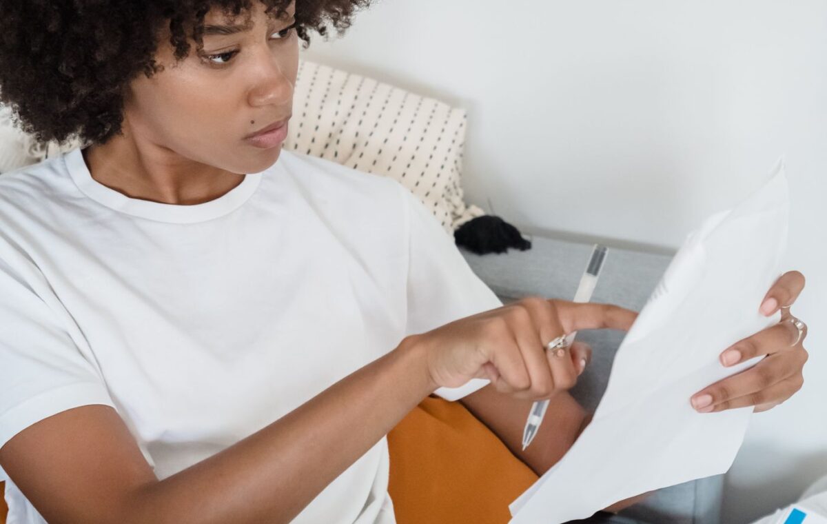 Mulher consulta documentos enquanto trabalha em um computador portátil