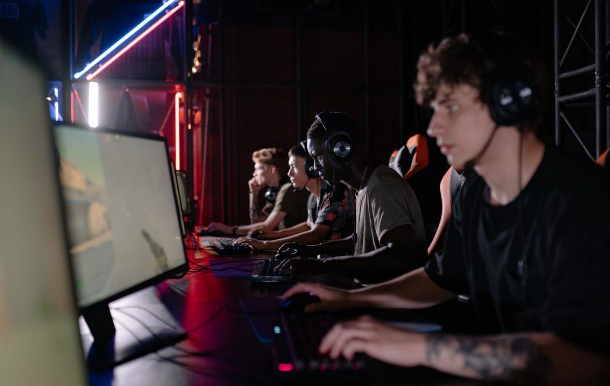 Jogadores usando computadores e fones durante competição de esportes eletrônicos