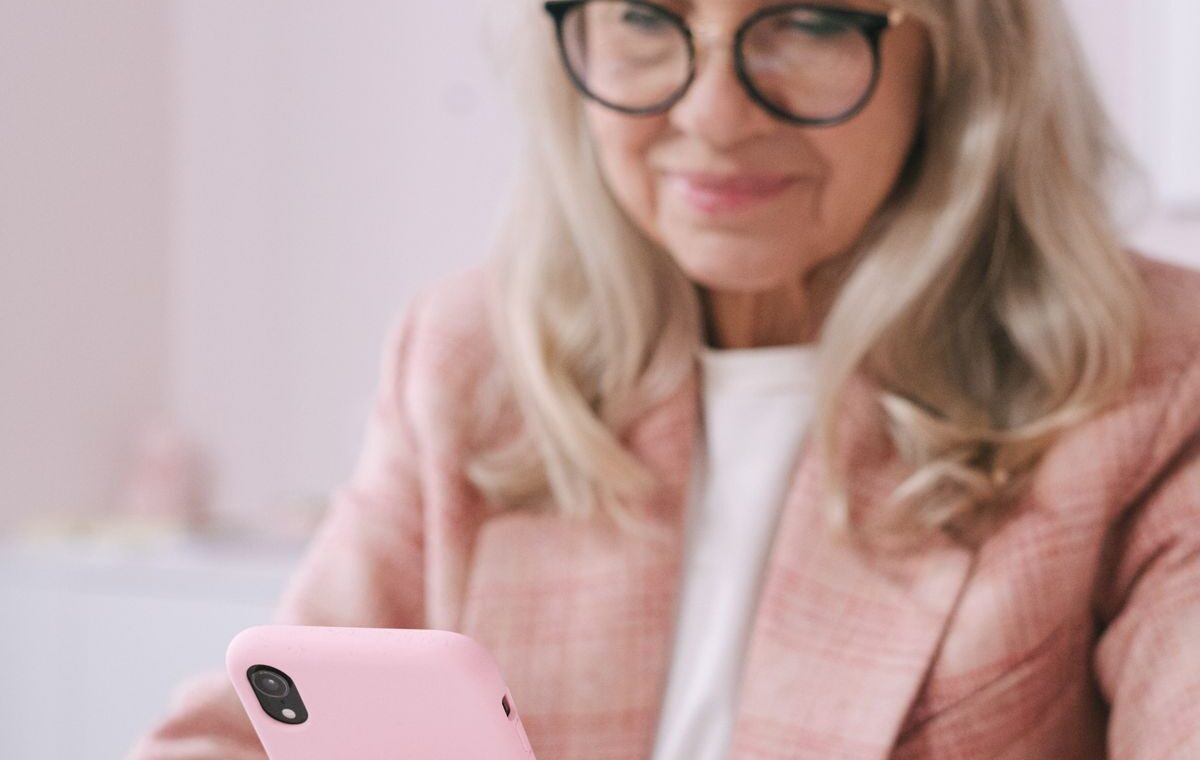 Mulher idosa consulta um telefone celular em casa