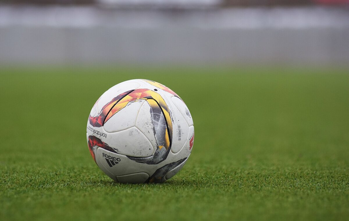 Bola de futebol sobre gramado, em fotografia ilustrativa