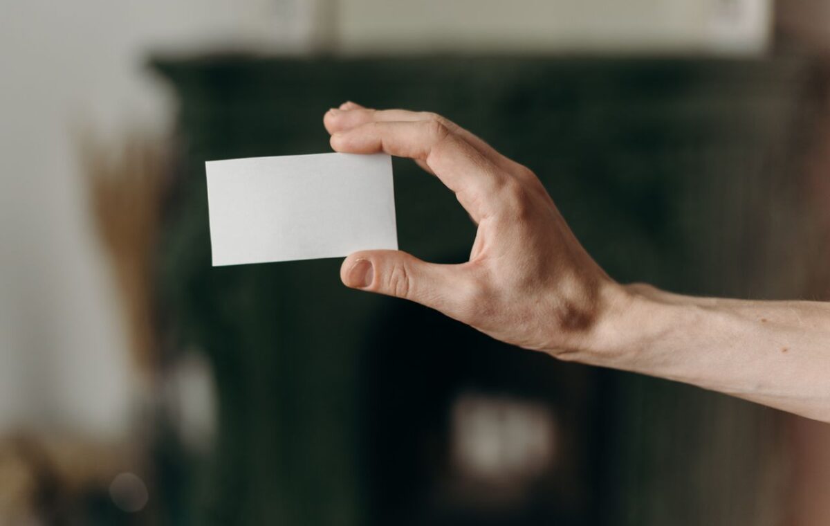 Mão segura um pequeno cartão branco sem informações impressas