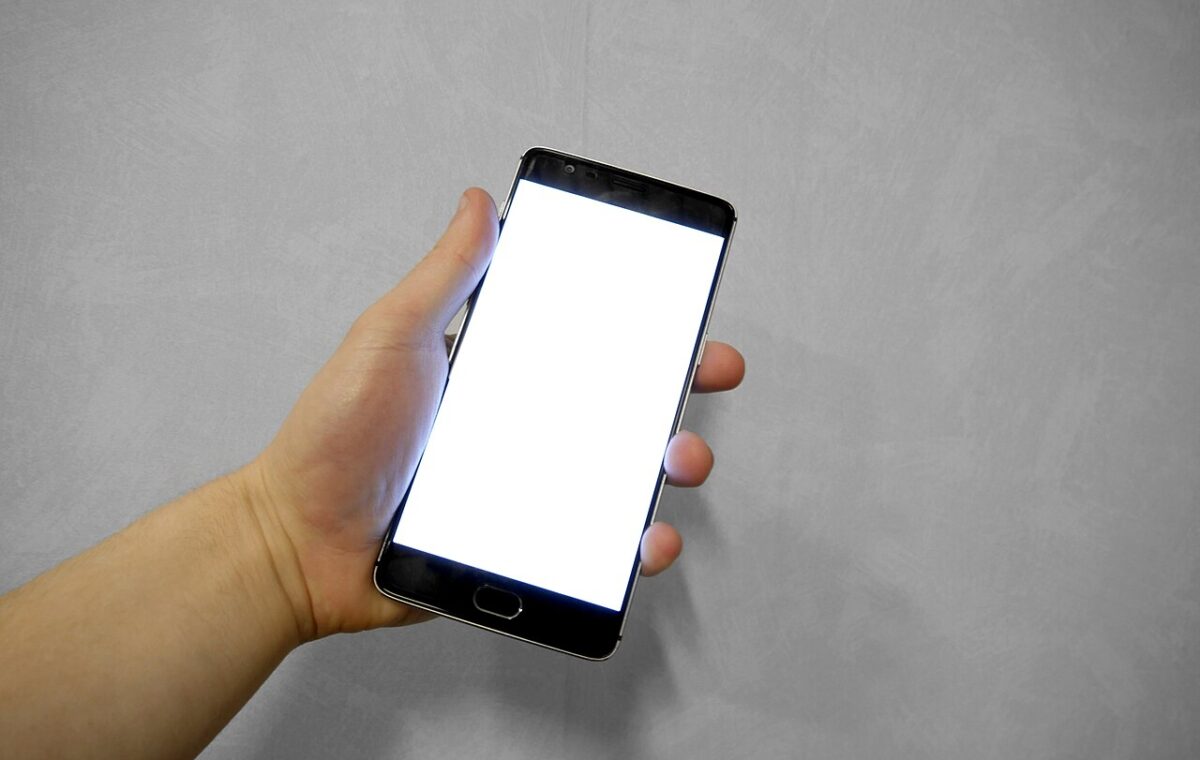 Mão segura telefone celular com a tela branca