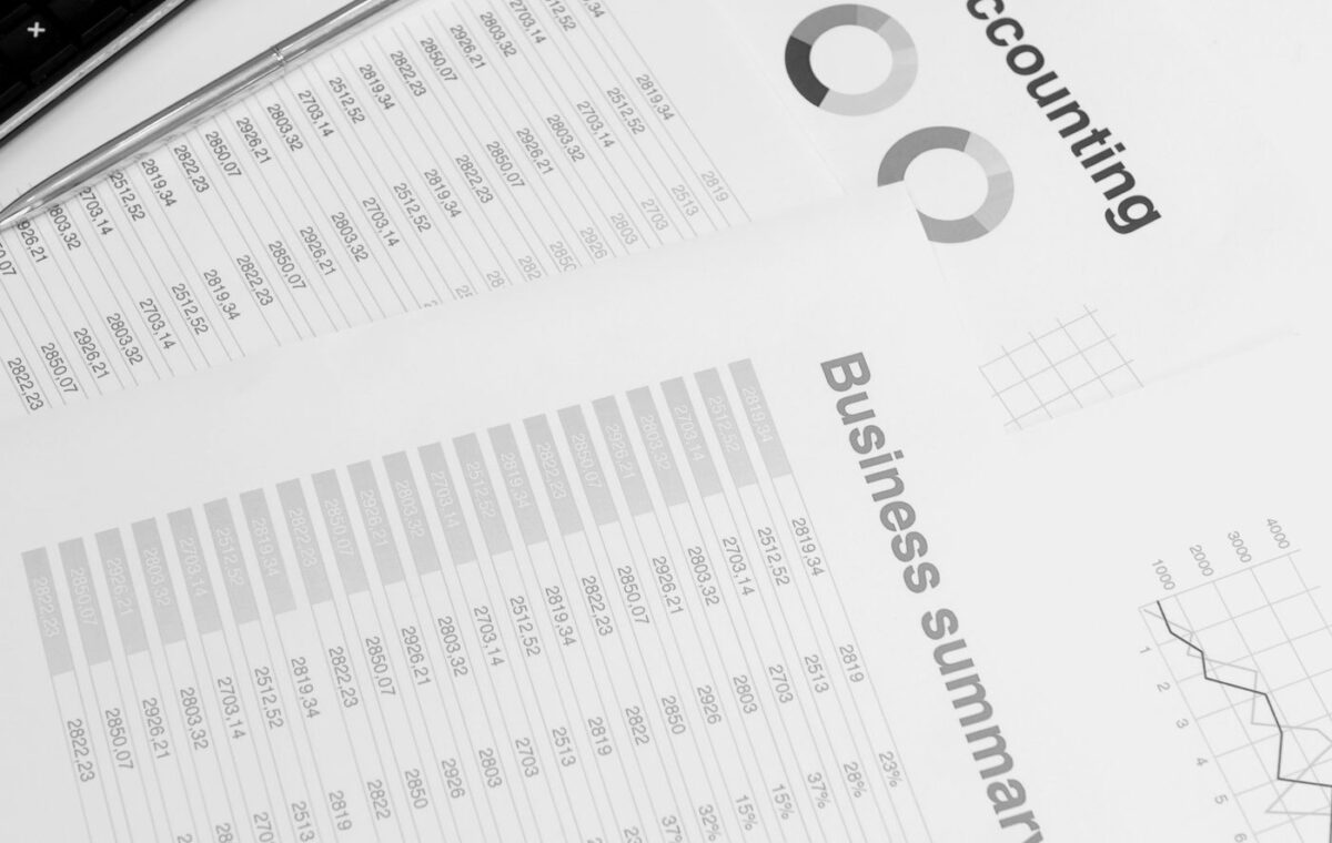 Mesa com computador portátil, calculadora e documentos financeiros