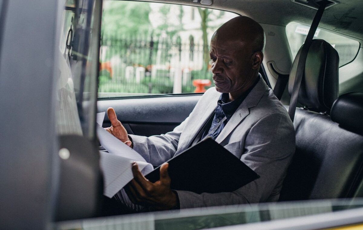 Homem lê documentos sentado dentro de um automóvel