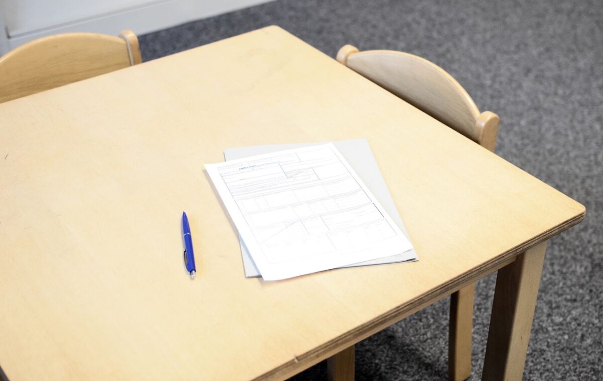 Documentos, caneta e pasta sobre mesa em sala de aula