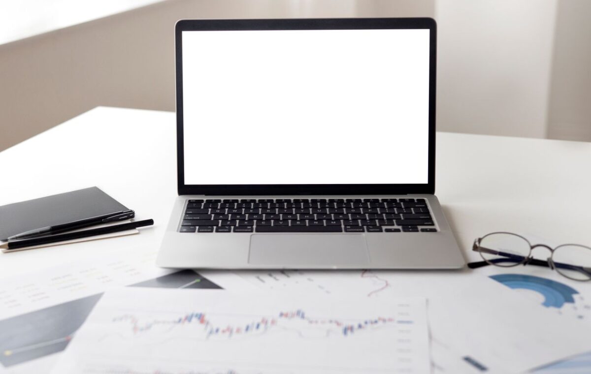 Notebook aberto ao lado de documentos financeiros sobre uma mesa