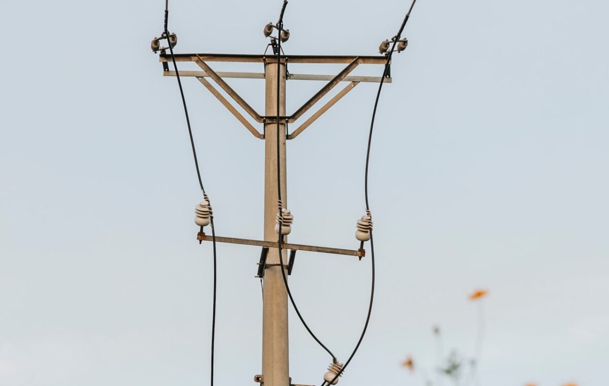 Poste com cabos de energia elétrica visto contra o céu
