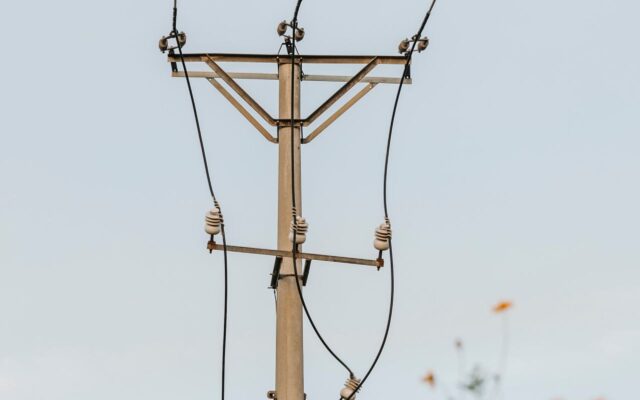 Poste com cabos de energia elétrica visto contra o céu